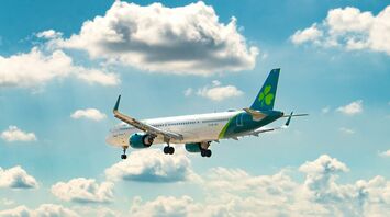 Aer Lingus aircraft in flight against a blue sky with scattered clouds