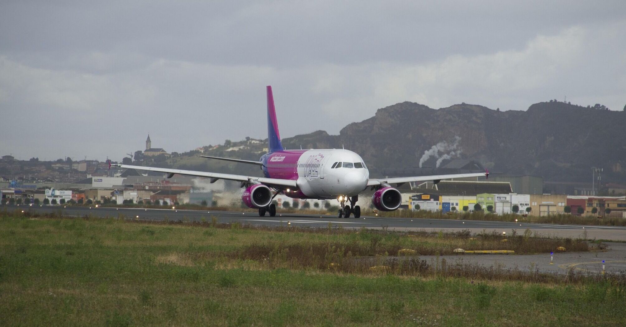 Wizz Air aircraft landing on a runway with a mountainous backdrop