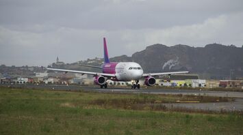 Wizz Air aircraft landing on a runway with a mountainous backdrop