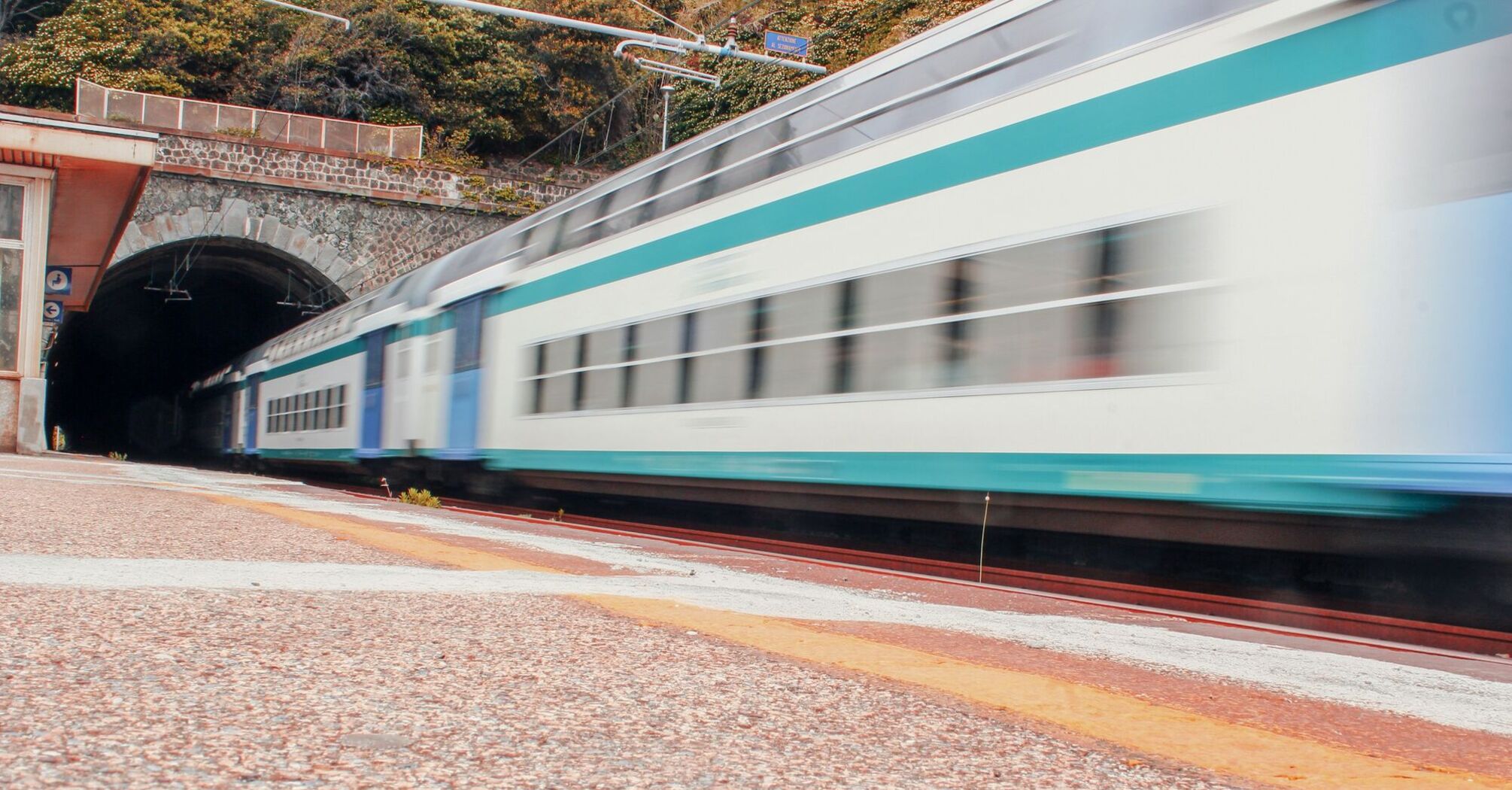 A high-speed train passing through a station near a tunnel, captured in motion