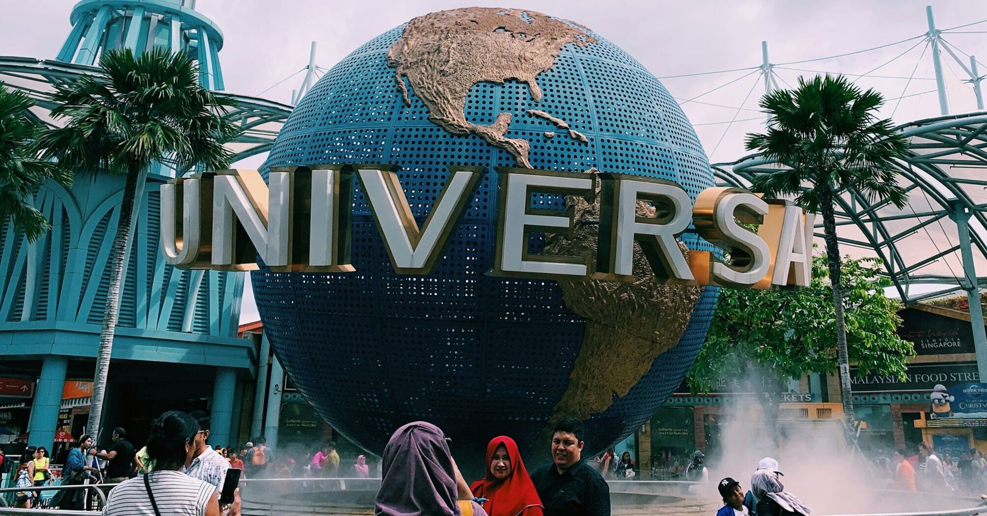 Universal Studios Singapore entrance with the iconic rotating globe and visitors taking photos