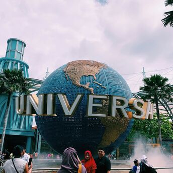 Universal Studios Singapore entrance with the iconic rotating globe and visitors taking photos