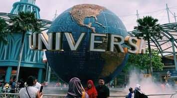 Universal Studios Singapore entrance with the iconic rotating globe and visitors taking photos