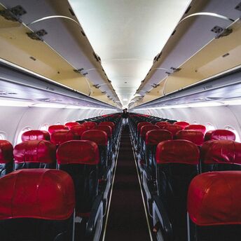 Interior of an AirAsia airplane with red and black seats, viewed from the aisle