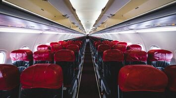 Interior of an AirAsia airplane with red and black seats, viewed from the aisle