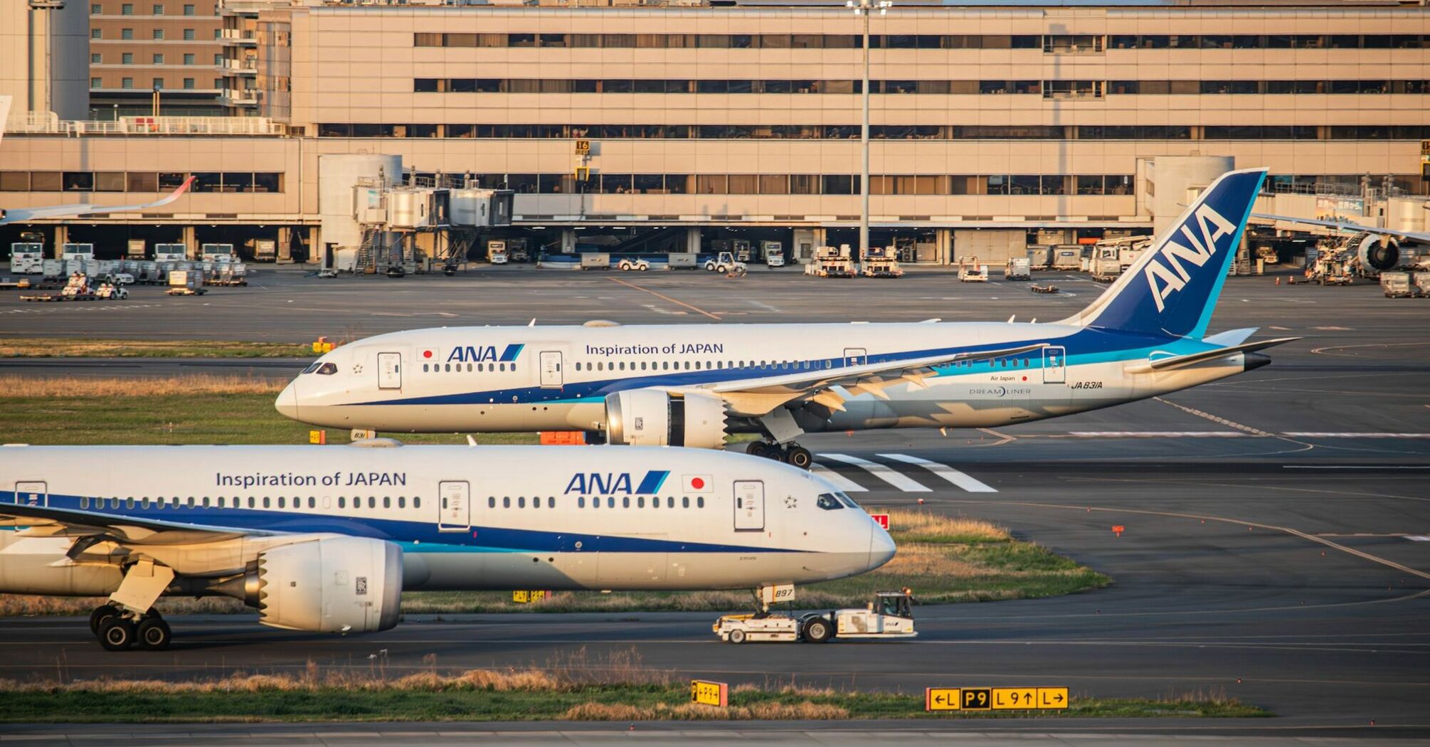 ANA aircraft parked at an international airport terminal during sunset