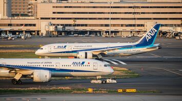 ANA aircraft parked at an international airport terminal during sunset