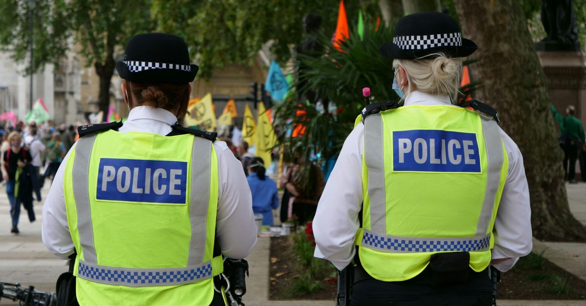 Two police officers in high-visibility vests and people in the background