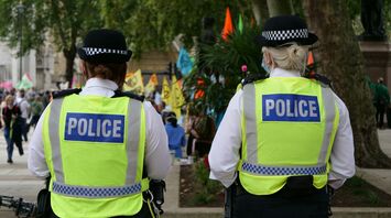 Two police officers in high-visibility vests and people in the background