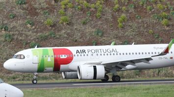 TAP Air Portugal aircraft on the runway with a green hillside in the background