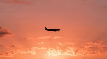 Airplane flying over the ocean at sunset with a dramatic sky
