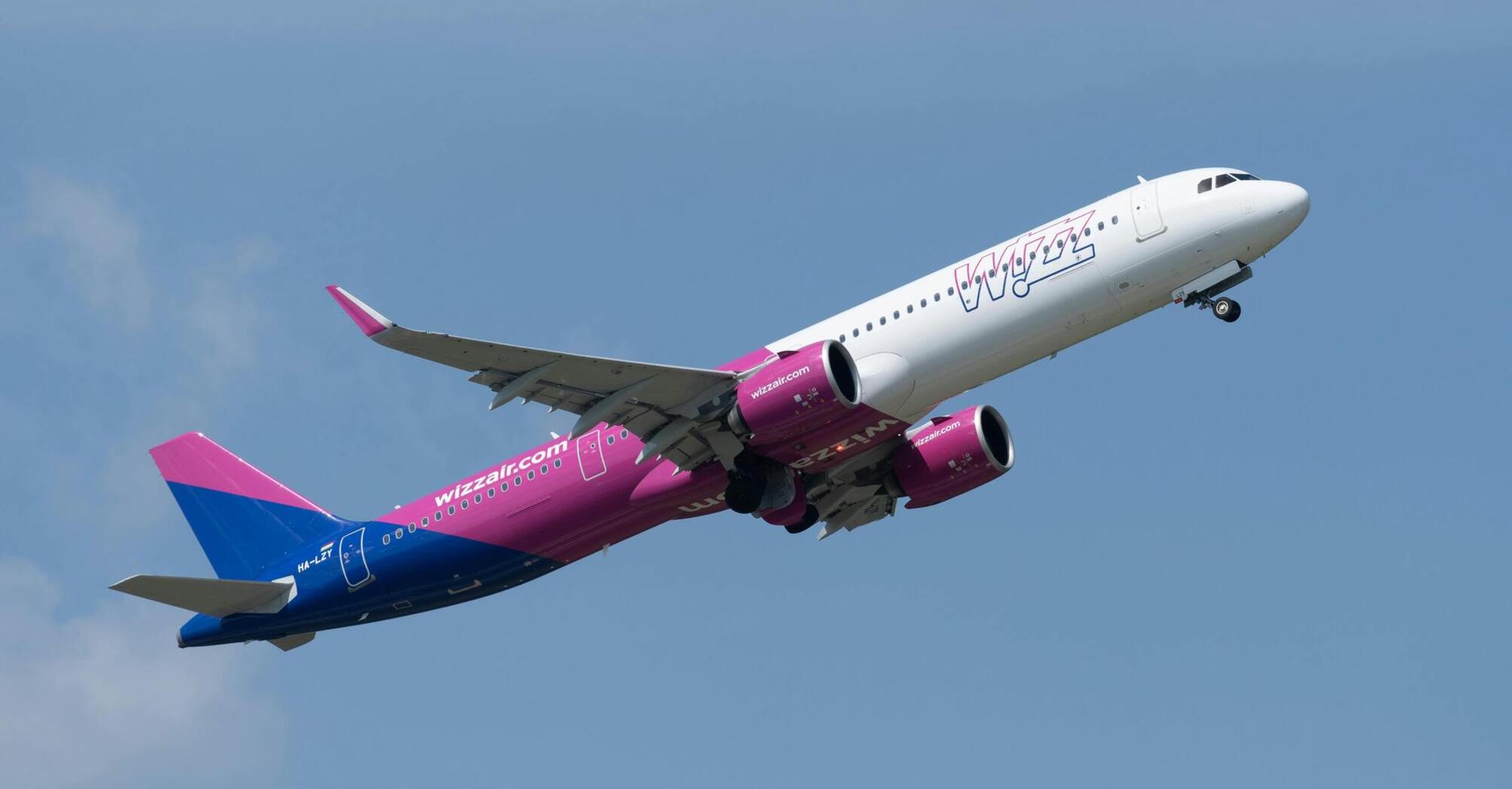 A Wizz Air plane taking off against a clear blue sky