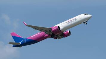 A Wizz Air plane taking off against a clear blue sky