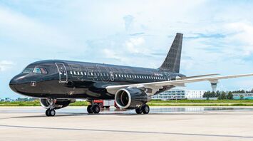 A beOnd luxury aircraft with a sleek black exterior parked on the runway under a blue sky