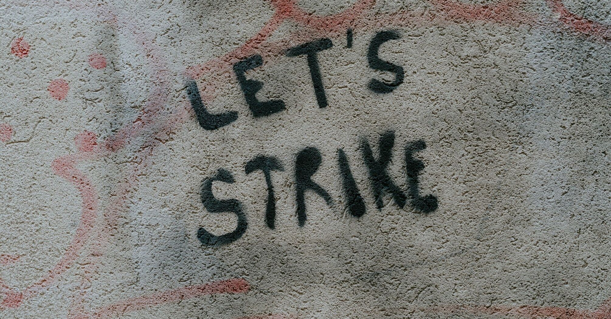 Graffiti on a wall reading "LET'S STRIKE" in black spray paint