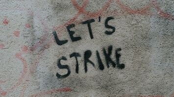 Graffiti on a wall reading "LET'S STRIKE" in black spray paint