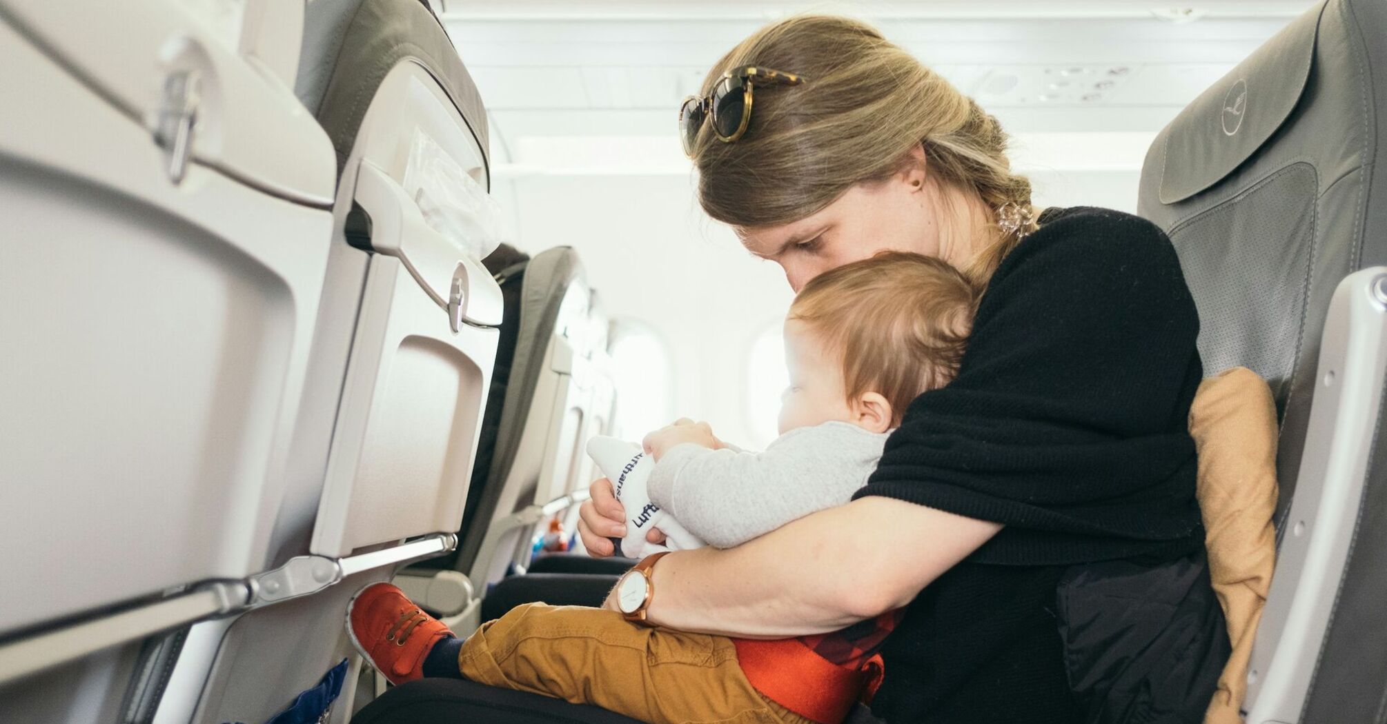 Mother holding her baby on an airplane, ensuring comfort and safety during the flight