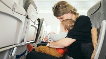 Mother holding her baby on an airplane, ensuring comfort and safety during the flight