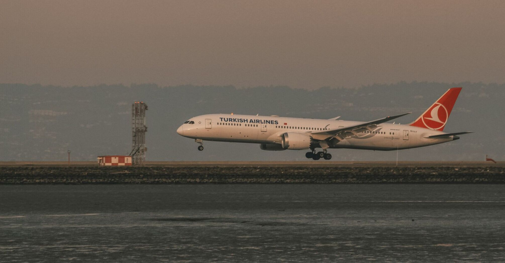 Turkish Airlines aircraft landing at an international airport during sunset