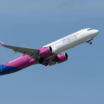 A Wizz Air aircraft taking off against a clear blue sky
