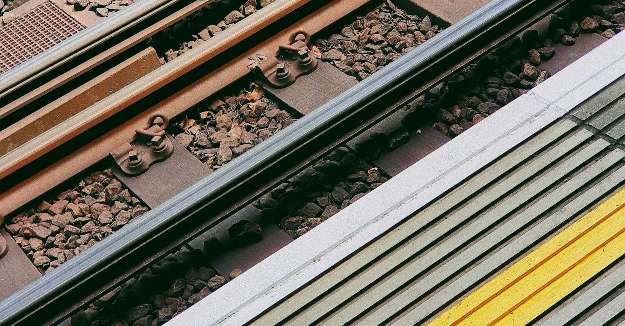 Close-up of railway tracks and station platform with a yellow safety line