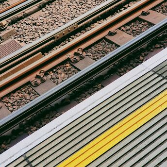 Close-up of railway tracks and station platform with a yellow safety line