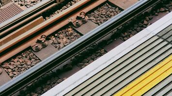 Close-up of railway tracks and station platform with a yellow safety line