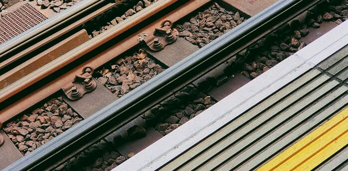 Close-up of railway tracks and station platform with a yellow safety line