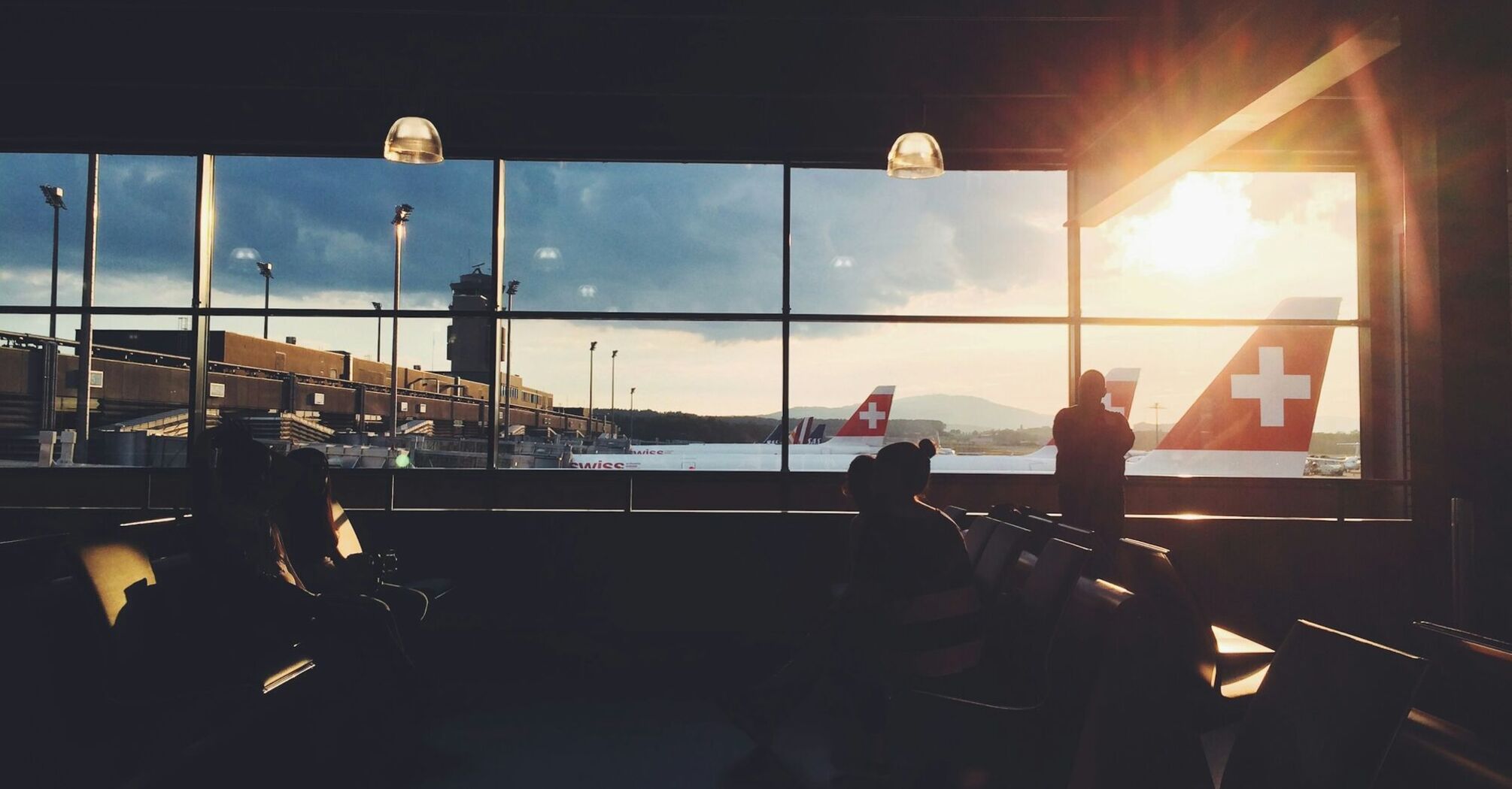 A sunset view from an airport terminal overlooking Swiss aircraft on the tarmac