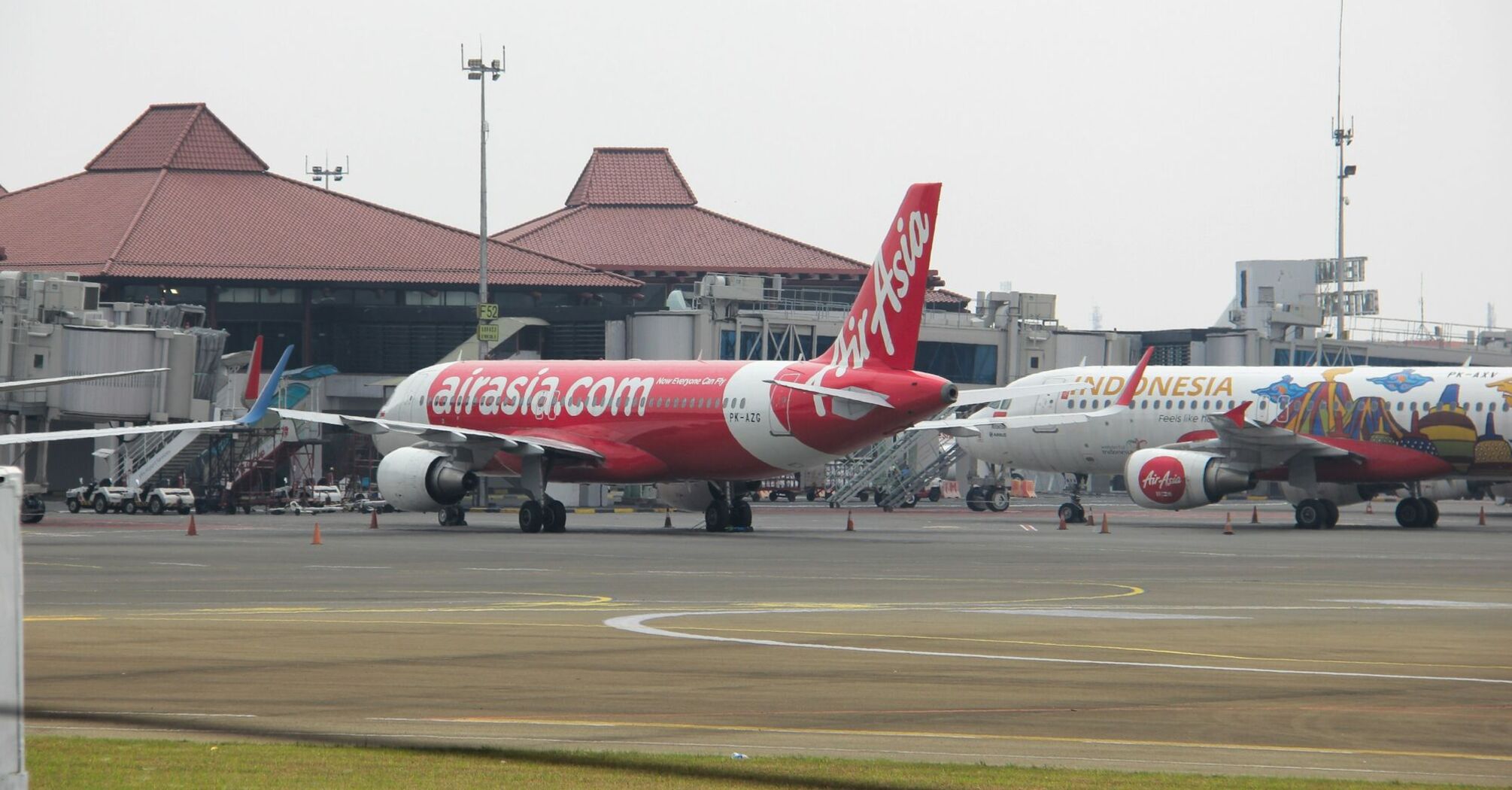 AirAsia aircraft parked at the airport terminal with another Indonesia AirAsia plane in the background