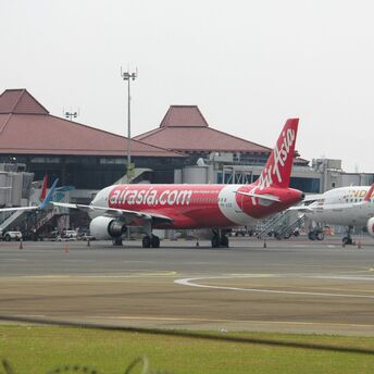 AirAsia aircraft parked at the airport terminal with another Indonesia AirAsia plane in the background