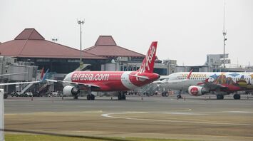 AirAsia aircraft parked at the airport terminal with another Indonesia AirAsia plane in the background