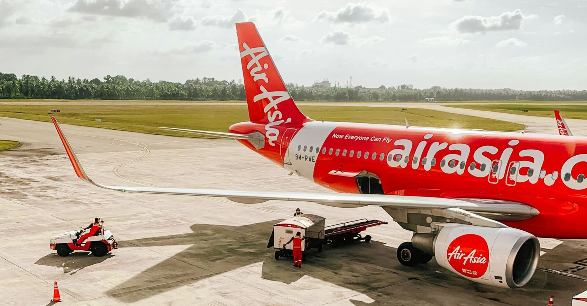 AirAsia aircraft on the tarmac with ground support vehicles preparing for departure