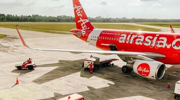 AirAsia aircraft on the tarmac with ground support vehicles preparing for departure