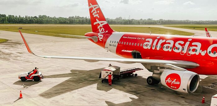 AirAsia aircraft on the tarmac with ground support vehicles preparing for departure