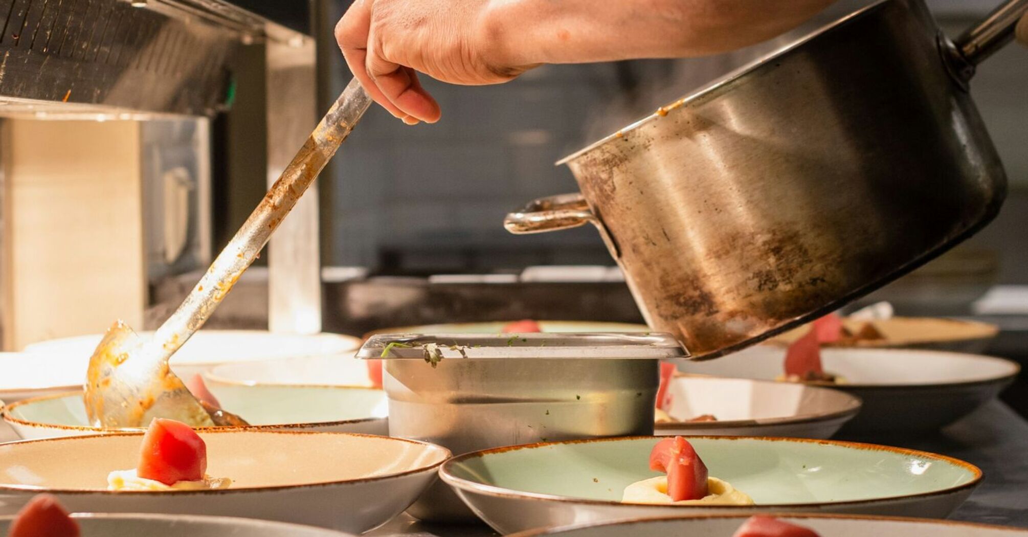 A chef in a kitchen carefully plating gourmet dishes with fresh ingredients