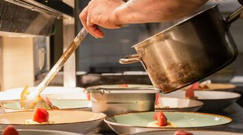 A chef in a kitchen carefully plating gourmet dishes with fresh ingredients