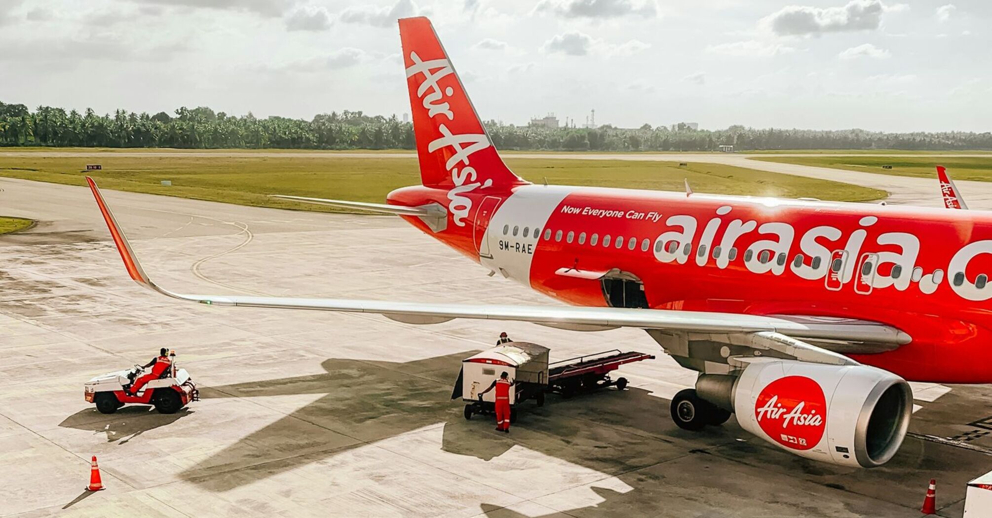 A parked AirAsia aircraft at the airport with ground support vehicles preparing for departure