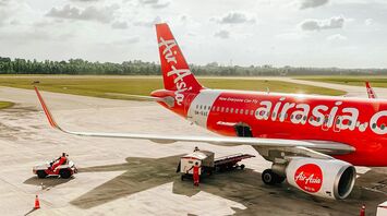 A parked AirAsia aircraft at the airport with ground support vehicles preparing for departure