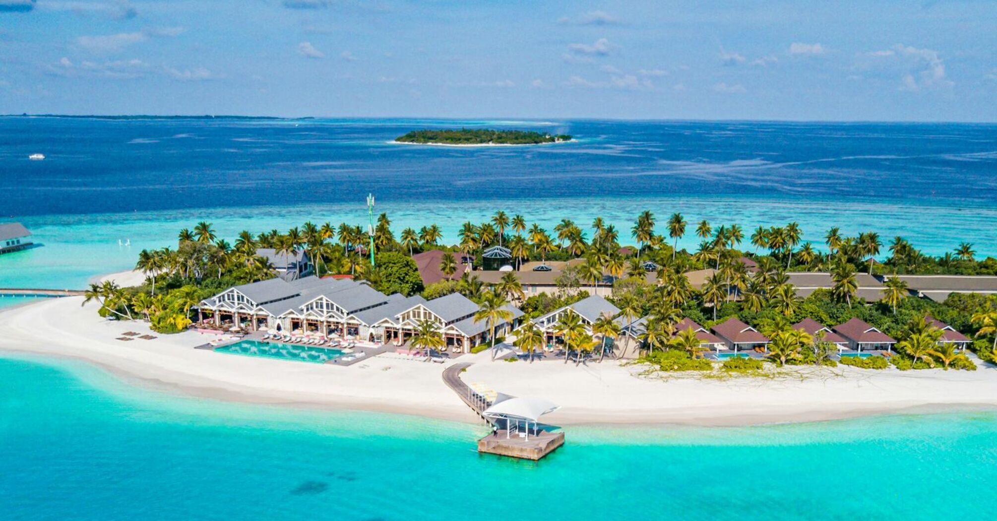 Aerial view of a tropical island resort in the Maldives with a speedboat approaching the shore