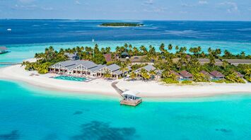 Aerial view of a tropical island resort in the Maldives with a speedboat approaching the shore