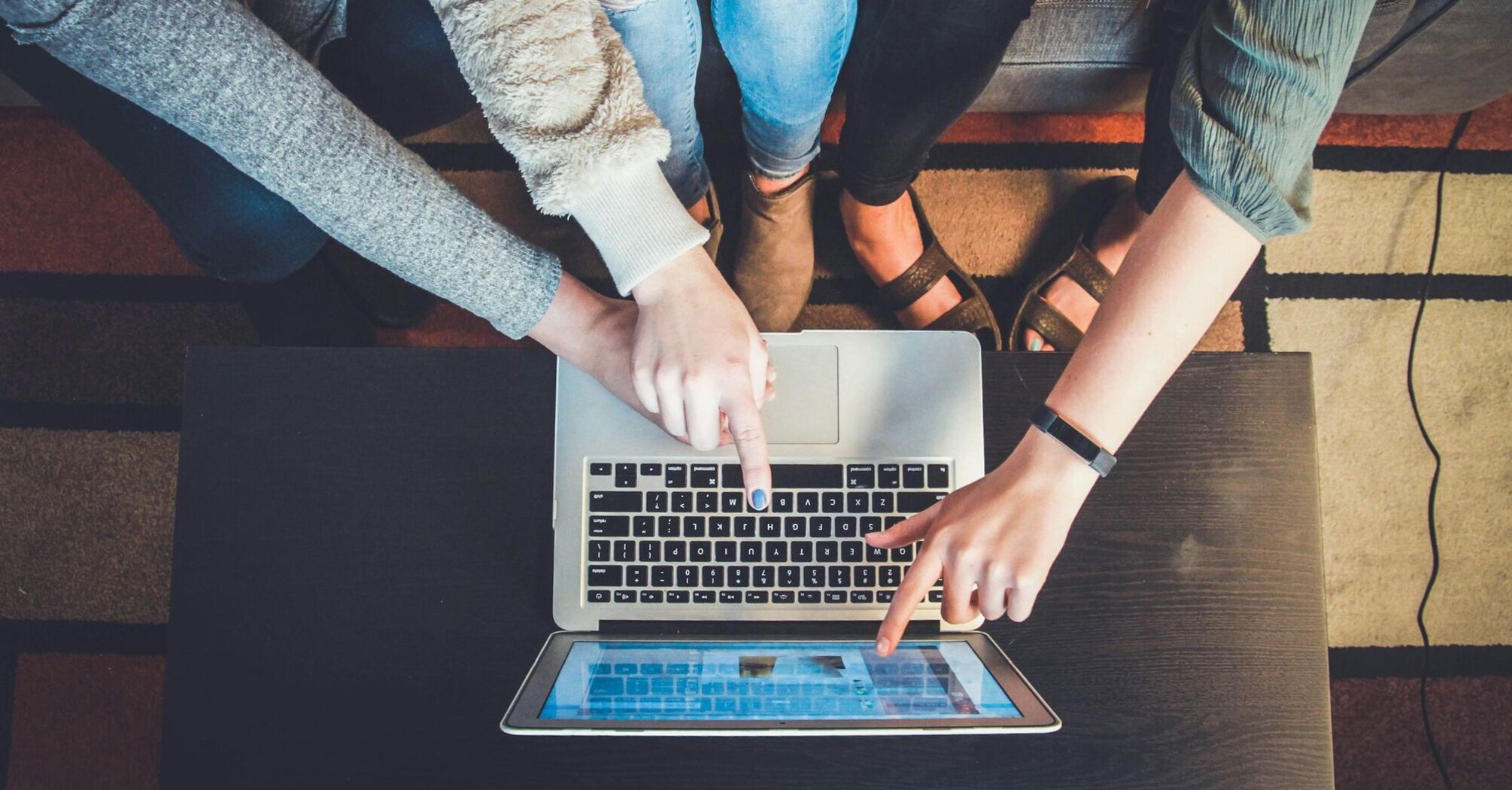 Three people pointing at a laptop screen while browsing online