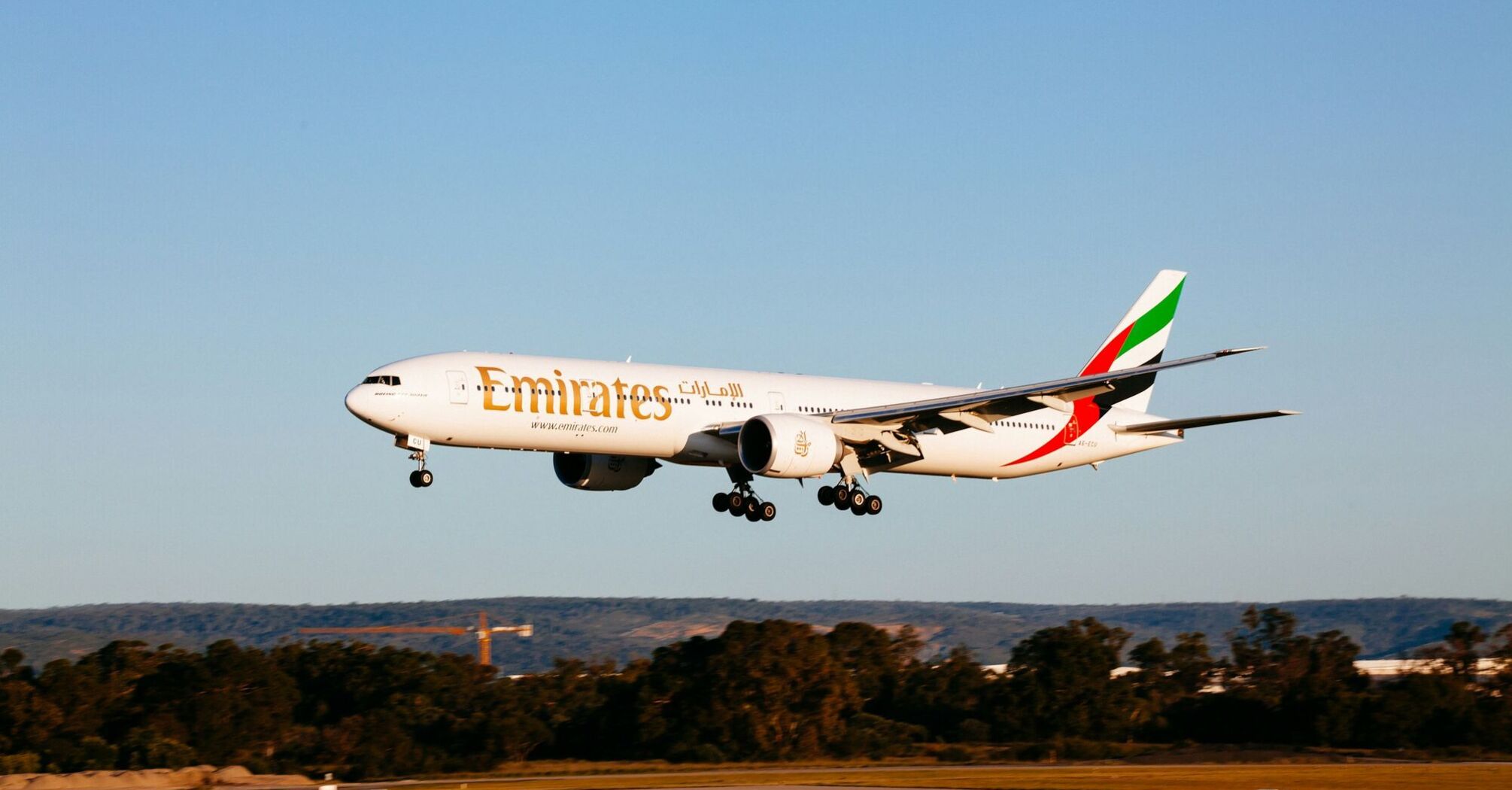 Emirates Boeing 777-300ER landing at an airport during golden hour