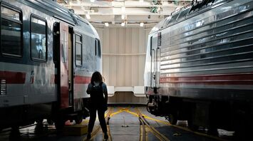 A Trenitalia Intercity train inside a ferry, with a person walking along the tracks