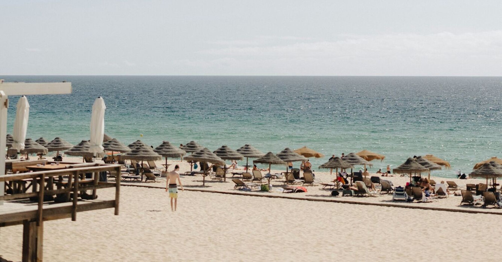 A sandy beach with sun umbrellas and lounge chairs overlooking the Atlantic Ocean under a clear sky