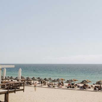 A sandy beach with sun umbrellas and lounge chairs overlooking the Atlantic Ocean under a clear sky