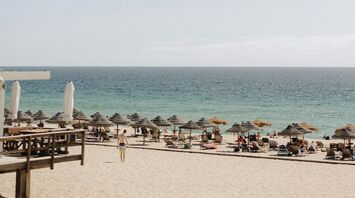 A sandy beach with sun umbrellas and lounge chairs overlooking the Atlantic Ocean under a clear sky