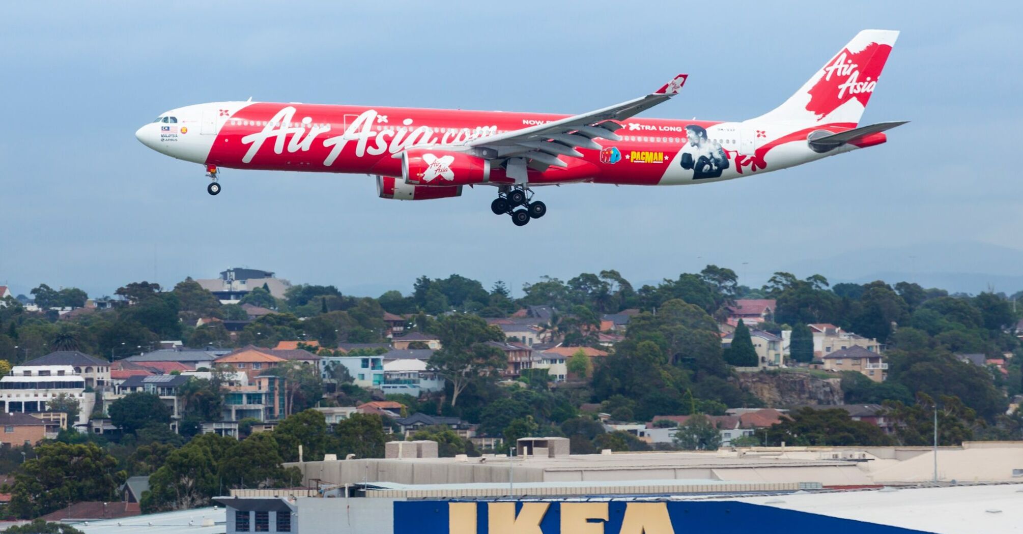 AirAsia aircraft landing with IKEA store in foreground