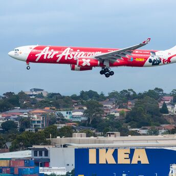 AirAsia aircraft landing with IKEA store in foreground