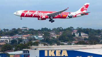 AirAsia aircraft landing with IKEA store in foreground